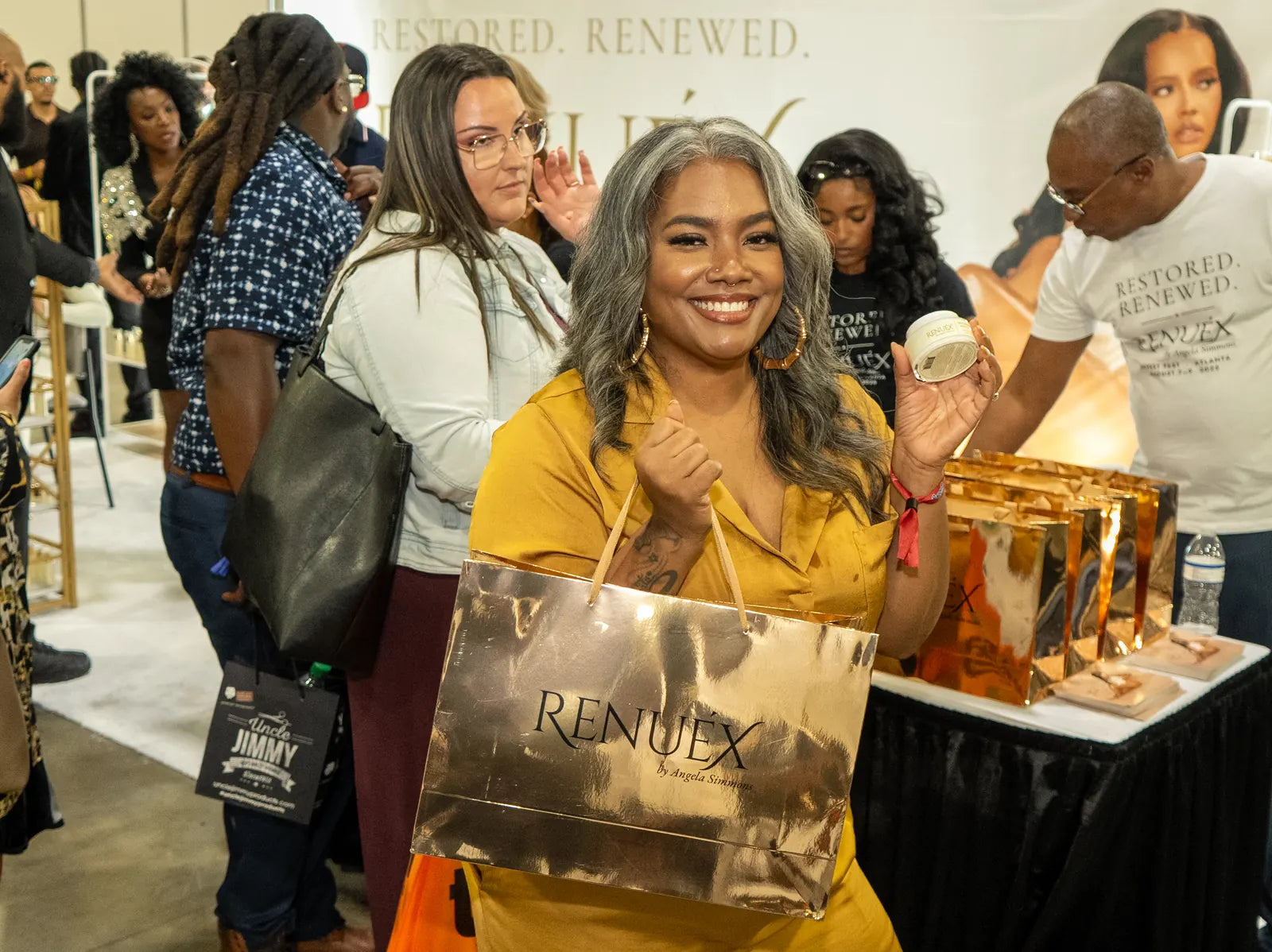 A visitor laughing with her gold bag and a jar of the crème