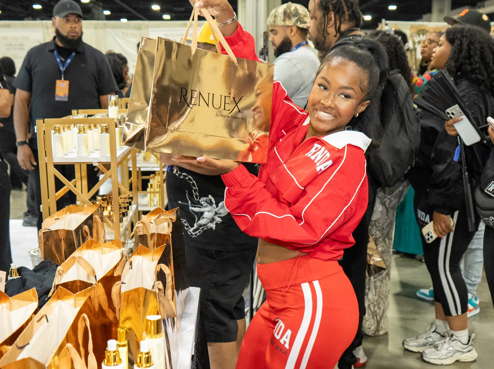 A visitor lifting her gold RENUEX bag in the crowd